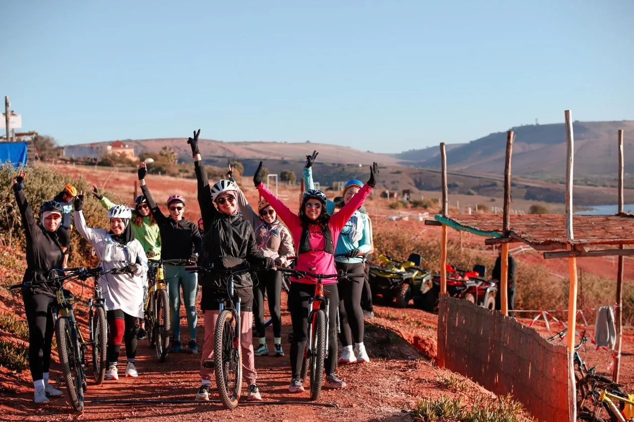 Un groupe à vélo, bras levés, au bord du lac d’Oued El Maleh